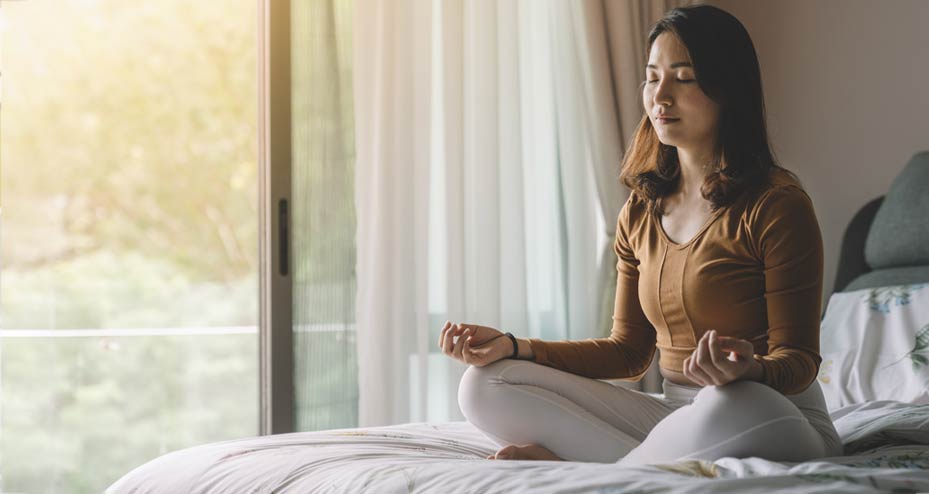 woman sitting on bed meditating