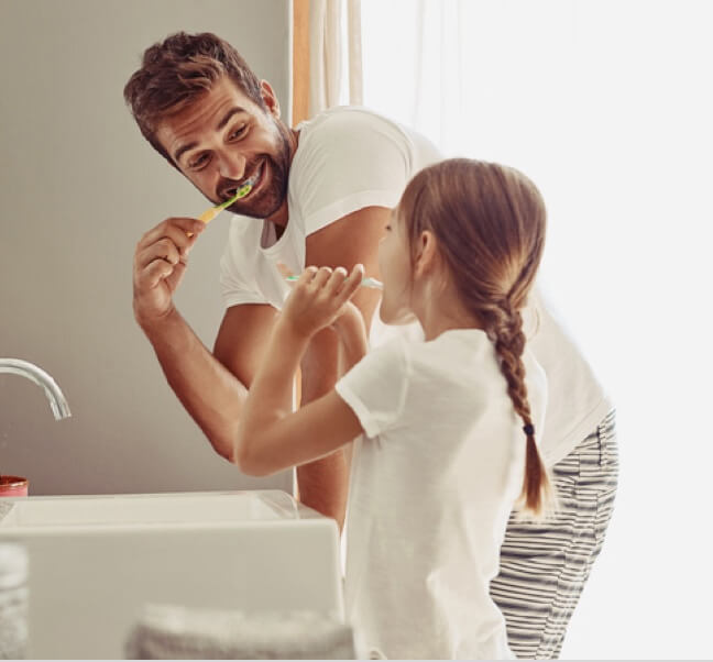 A father brushing teeth with a daughter